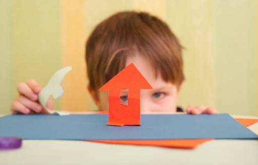 Small boy and little house made with color paper and scissors